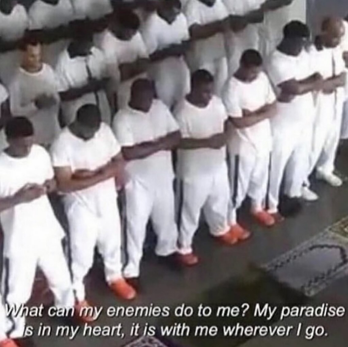 image of a group of men standing with heads bowed and hands folded in prayer. text reads 'What can my enemies do to me? my paradise is in my heart, it is with me wherever i go.'